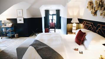 A hotel room with a large bed, a chair, a desk, and a window with curtains.