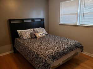 A bed with a patterned bedspread, a headboard, and a pillow with text. - The Quiet Zone in Calumet City (Calumet City)