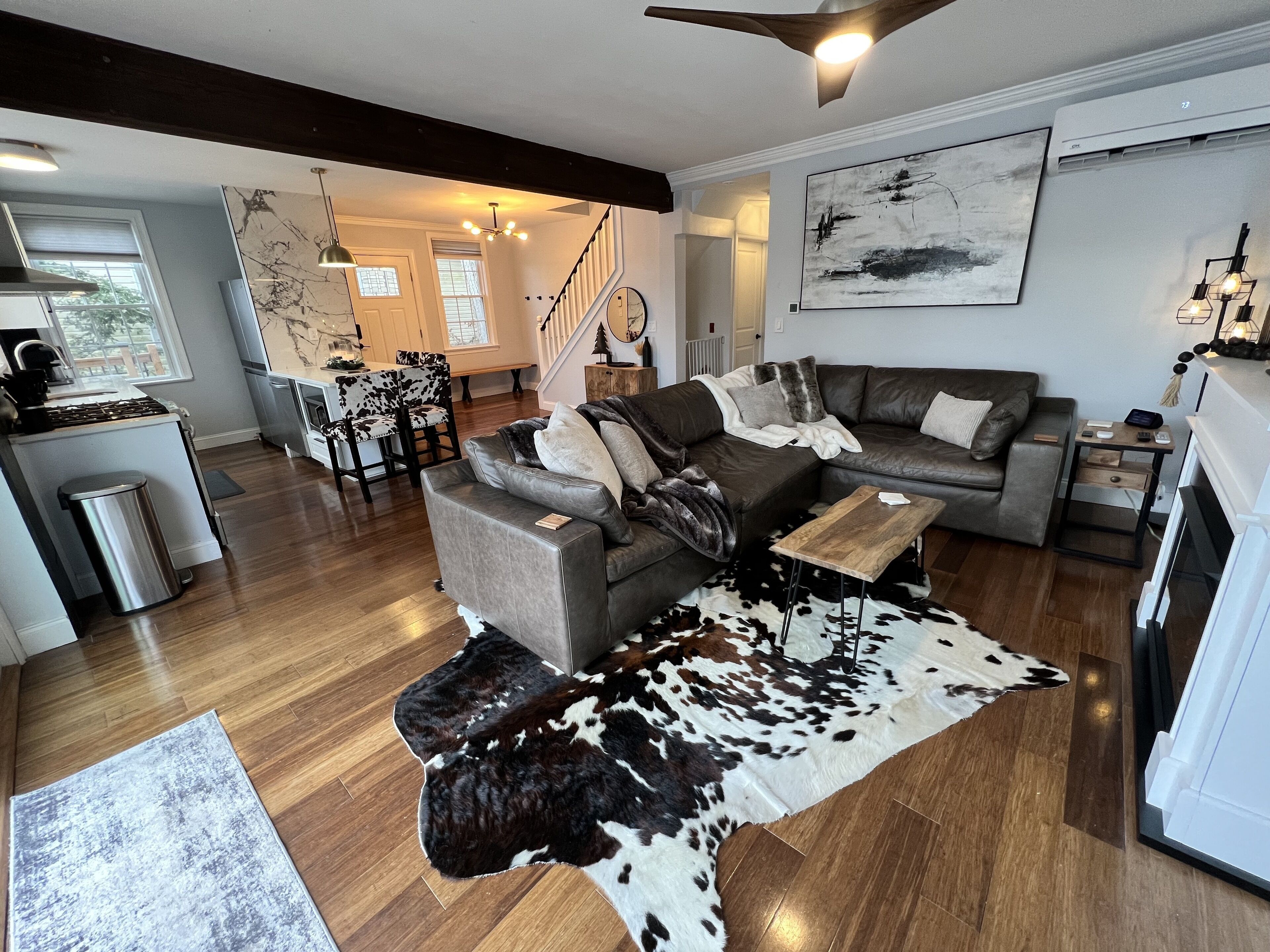 Un salon moderne avec un canapé en cuir, une table basse en bois et un tapis en peau de vache.