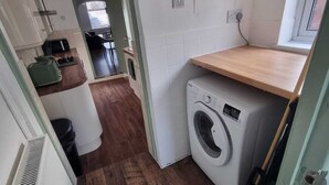 Una cocina compacta con lavadora, encimera de madera y un ventanal.