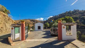 A gated entrance to a property with a small building in the background, a parked van, and a clear sky. - Cubo's Finca La Curva High Privacy / Private pool / Views (Pizarra)