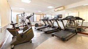 Un gimnasio con cintas de correr, bicicletas estáticas y elípticas.