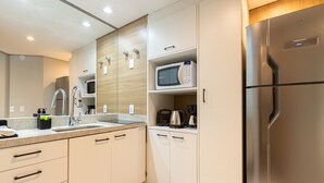Una cocina moderna con un refrigerador de acero inoxidable, un microondas y una cafetera sobre la encimera.