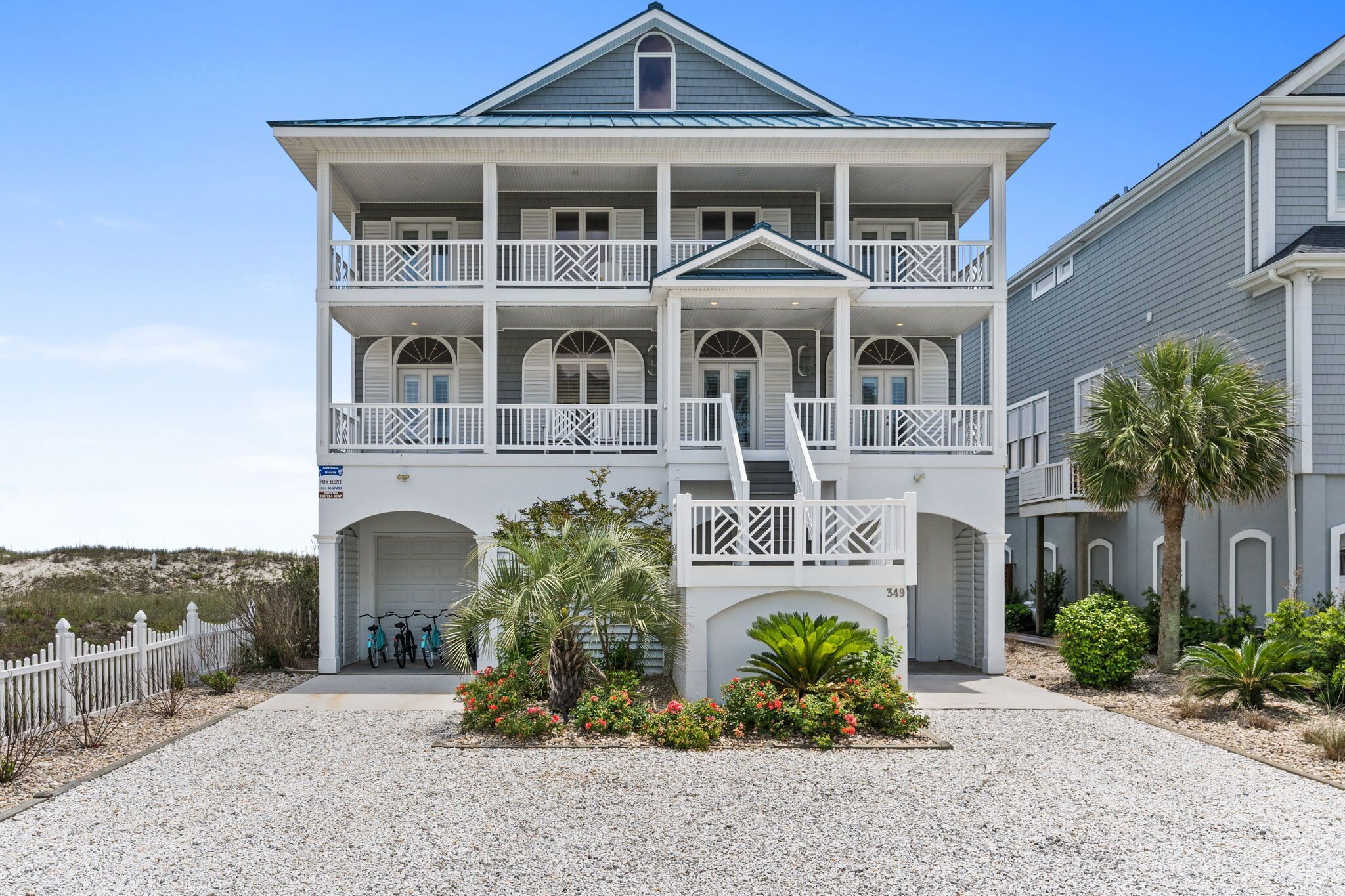 A multi-story building with balconies, a covered entrance, and a gravel driveway.