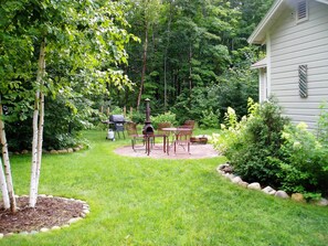 Un jardin avec un barbecue, un coin salon extérieur et une cheminée.