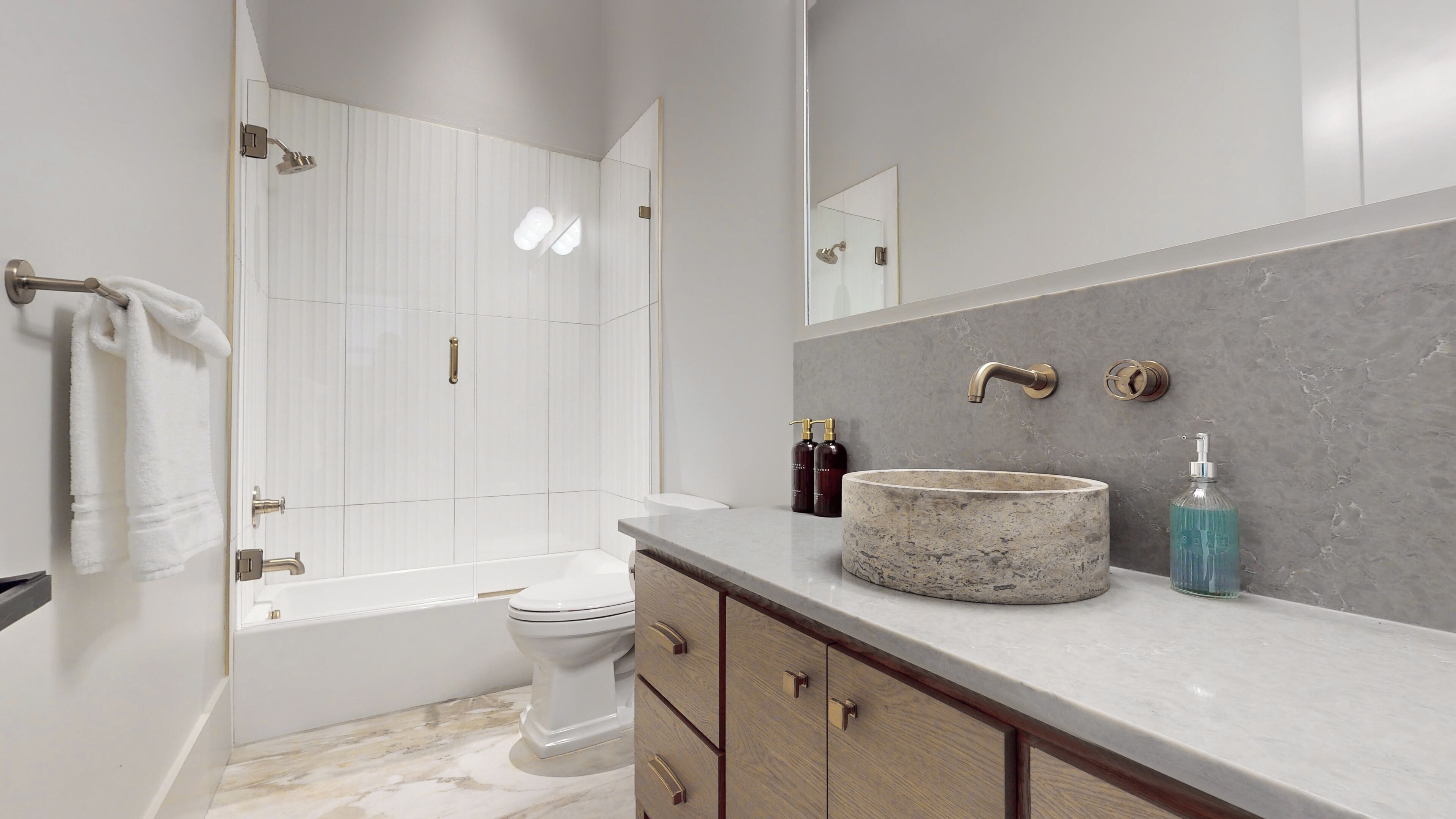 Une salle de bain moderne comprenant une baignoire, des toilettes, un meuble-lavabo avec un grand évier et un espace douche.
