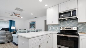 A modern kitchen with white cabinetry, a black stove, and a microwave. - Private 2 BR steps from beach on Casey Key (Nokomis)
