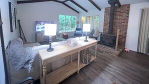 Ein Wohnzimmer mit Holztisch, zwei Lampen, Kamin und Fernseher.