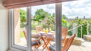 A patio with a table and chairs, a glass door leading to a garden, and a view of the surrounding area. - 3 bedroom accommodation in Summerbridge, near Pateley Bridge (Summerbridge, near Pateley Bridge)