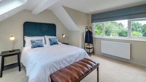 A bedroom with a large bed, a bench, a radiator, a window with a view, and a hanging coat rack. - 3 bedroom accommodation in Summerbridge, near Pateley Bridge (Summerbridge, near Pateley Bridge)