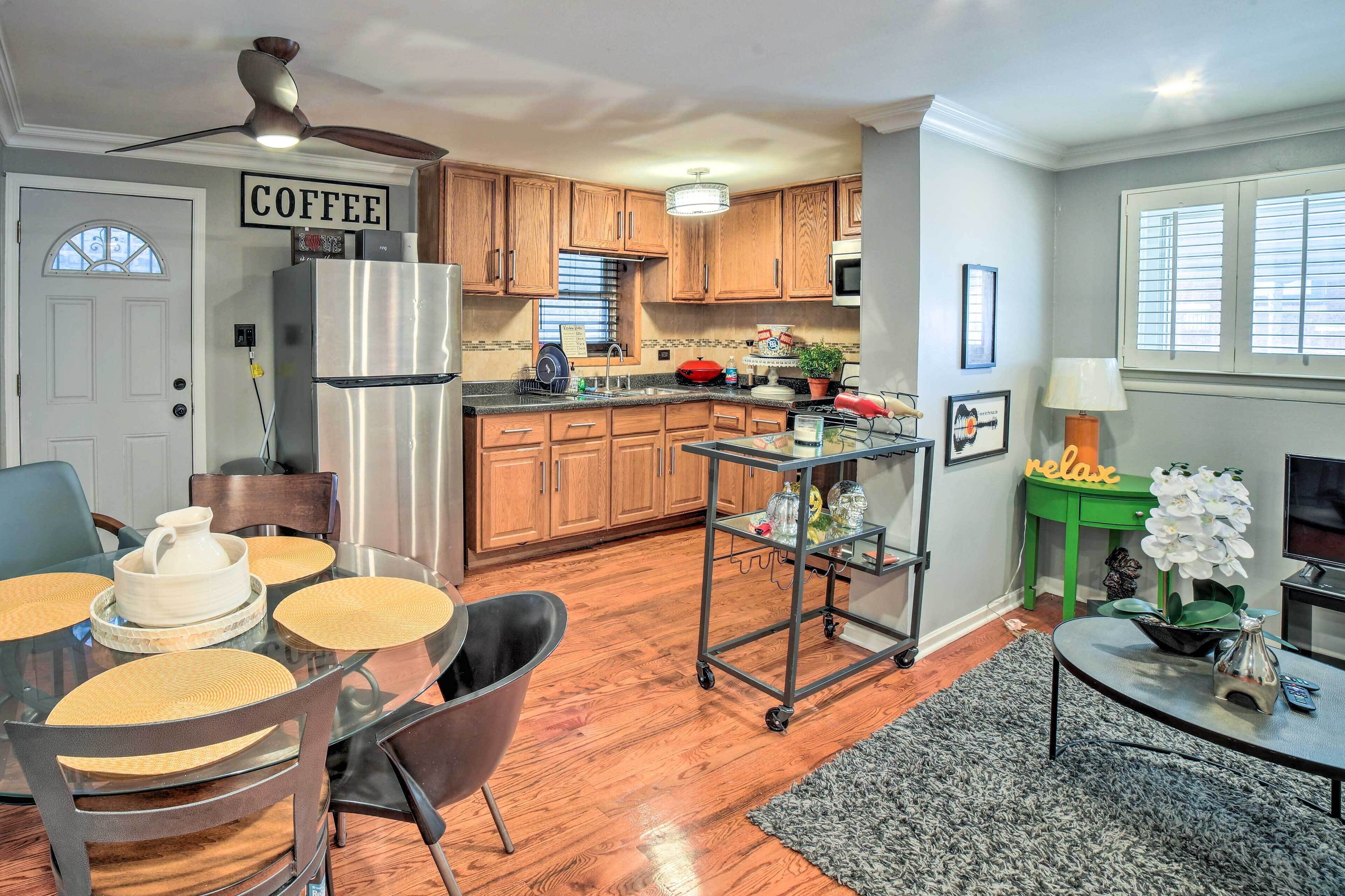 A kitchen with wooden cabinets, a stainless steel refrigerator, and a dining area with a glass table and chairs.
