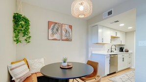 A modern dining area with a round table, two chairs, a hanging plant, and a kitchen in the background. - 2 Mi to Old Town: Home w/ Pool Access & Patio (Scottsdale)