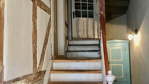 A staircase with wooden steps and a white balustrade, leading to a door with a window.