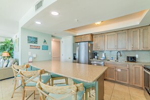 A kitchen with a central island, wooden cabinets, and a refrigerator. - Solace-Edgewater 613T3 Beachfront-Fully Renovated! Luxurious Walk-In Shower! (Panama City Beach)