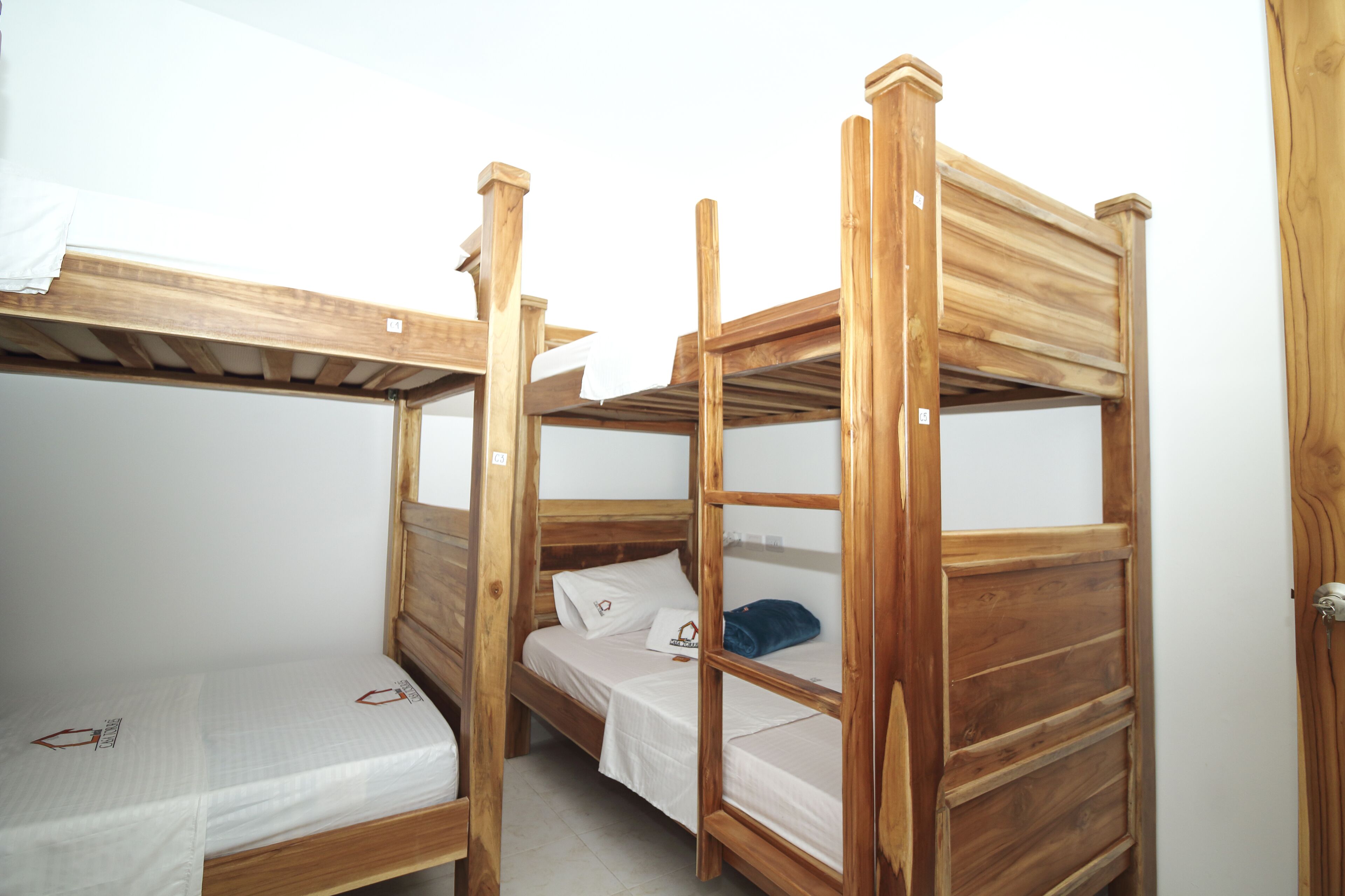 A bunk bed room with wooden frames and white bedding.