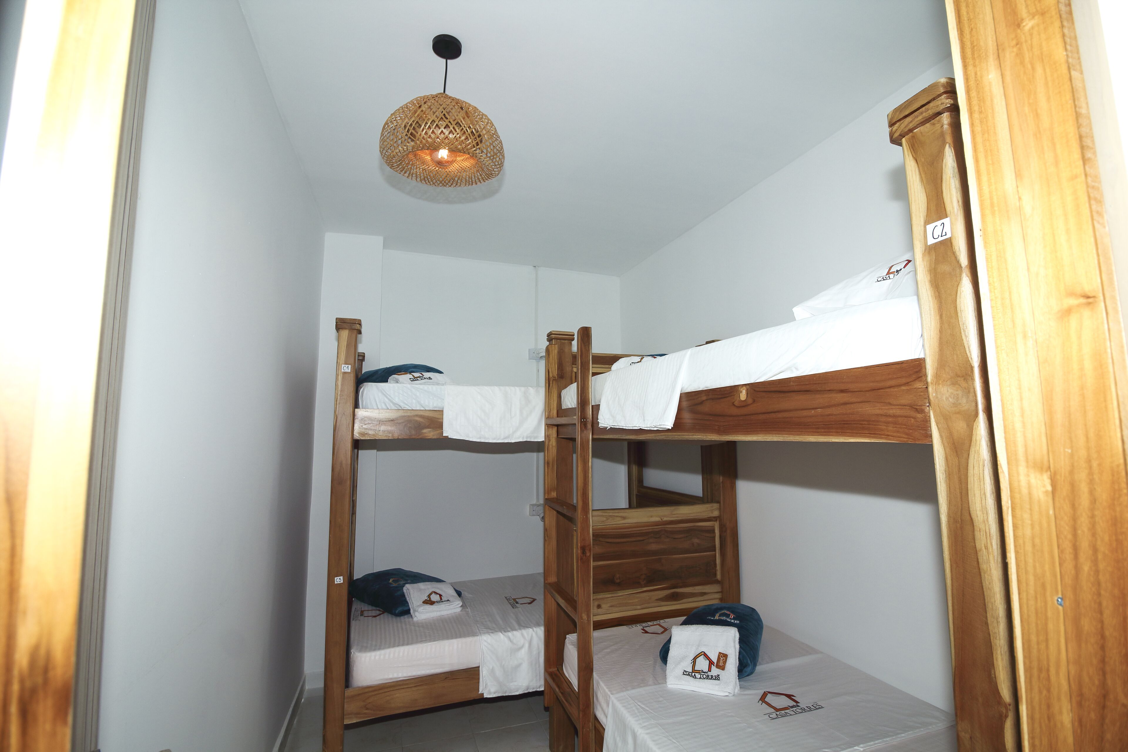 A bunk bed room with a woven light fixture above.