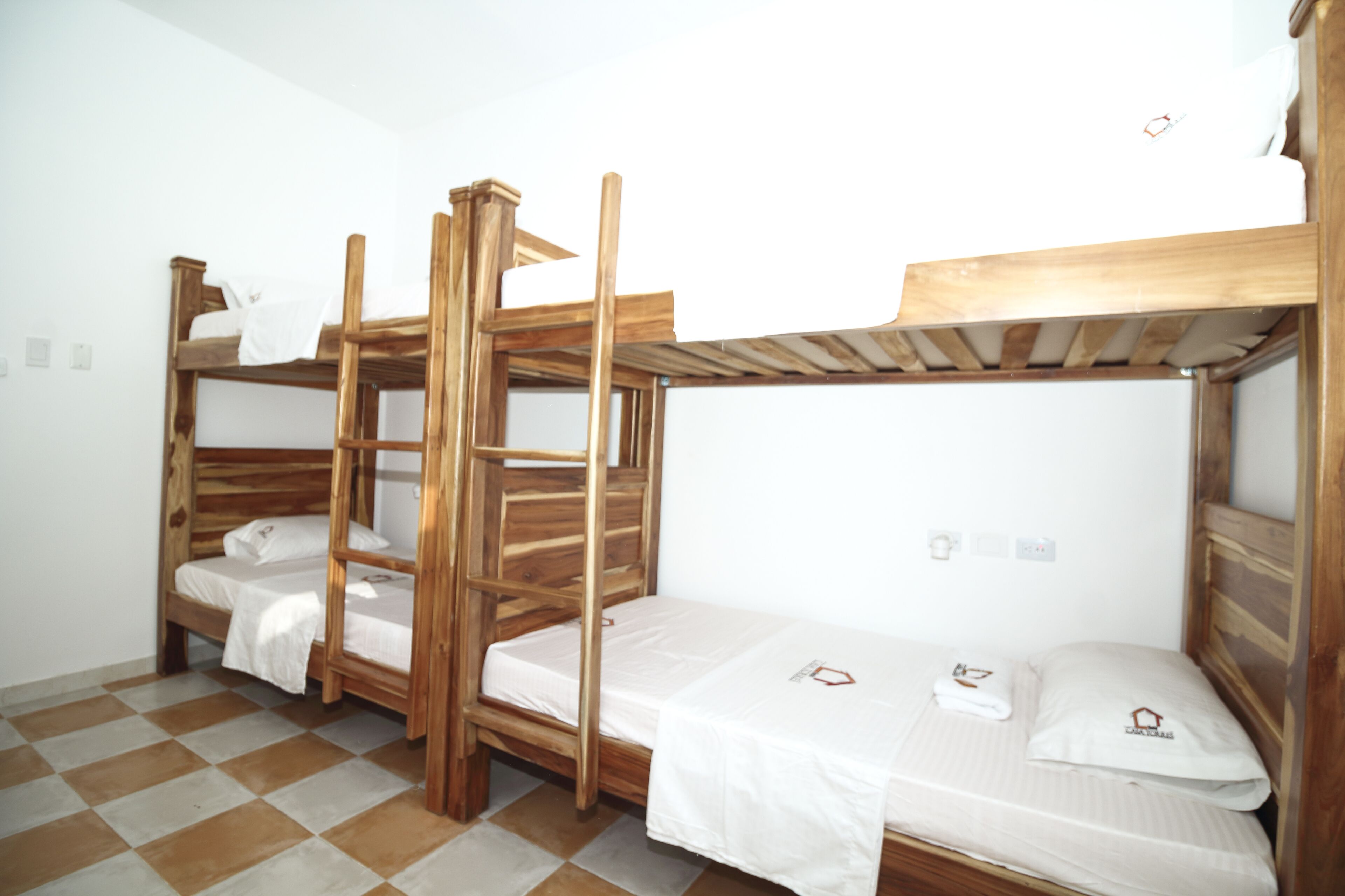 A room with three wooden bunk beds, each with a white mattress and pillow.