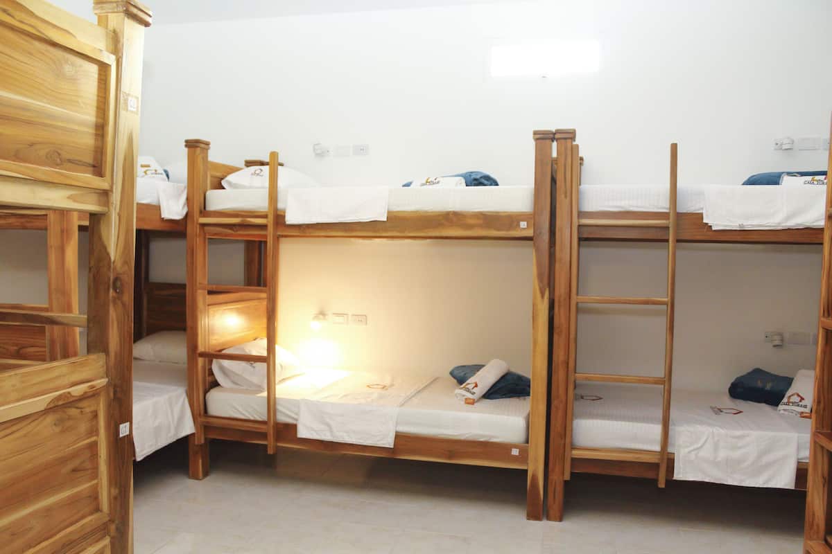 A bunk bed room with wooden frames and white bedding.