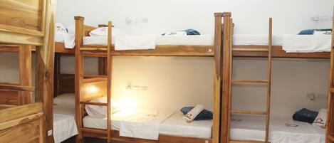 Dormitorio con literas de madera y ropa de cama blanca.