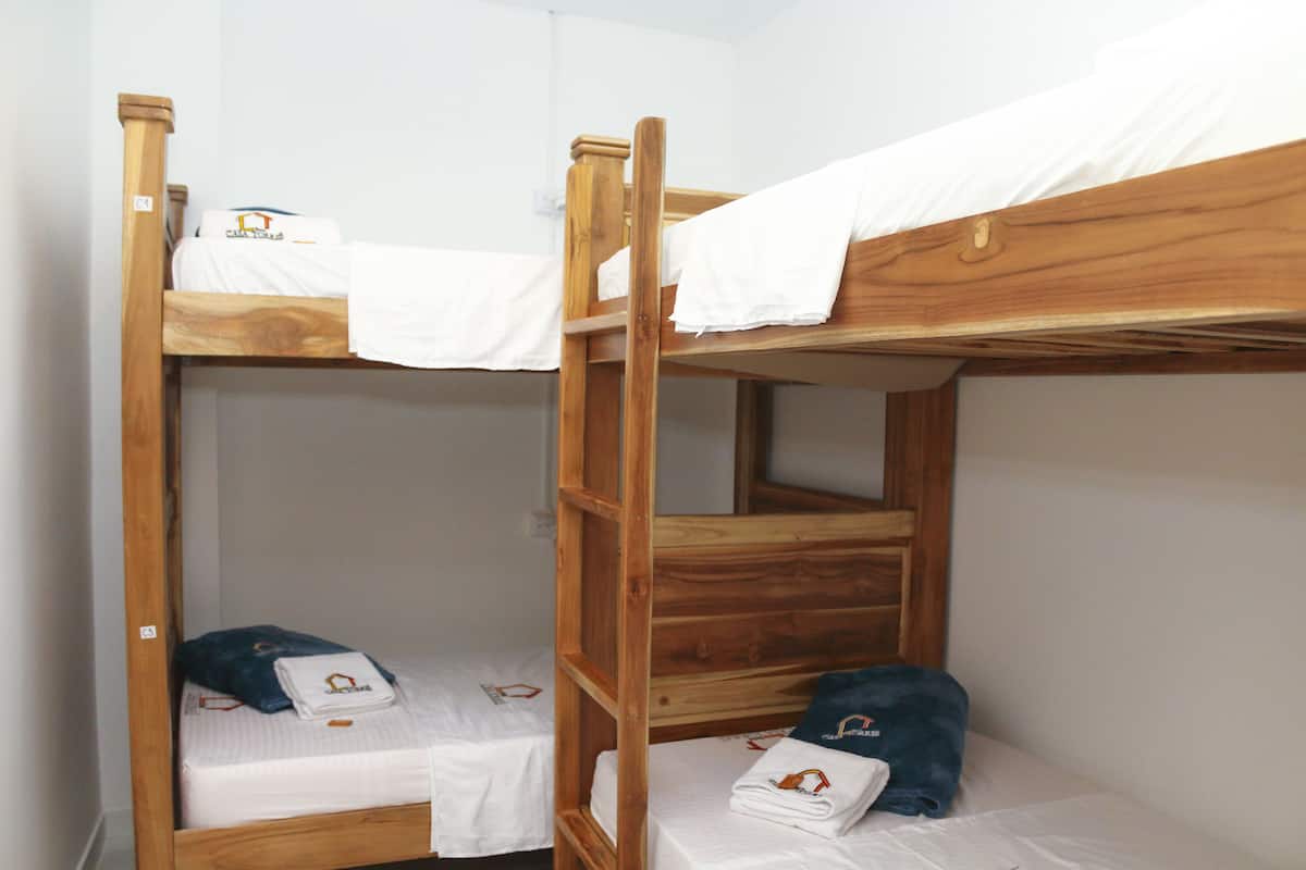 Two bunk beds with wooden frames and white bedding.