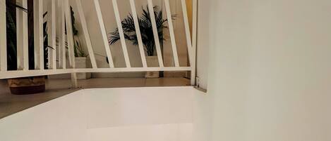 A staircase with white railings and a potted plant on the landing.