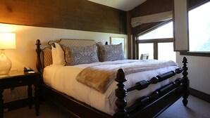 A neatly made bed with patterned pillows, a bedside lamp, and a window with curtains. - Viking Two Bedroom Loft 2 Apartment Hotel by RedAwning (Park City)