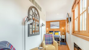 A cozy room with a bed, a chair, a lamp, and a fireplace.