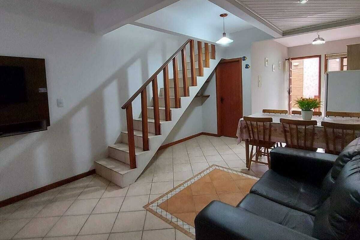 Ein geräumiger Wohnbereich mit Treppe zu einer oberen Ebene, einem Essbereich und einem an der Wand befestigten Flachbildfernseher.