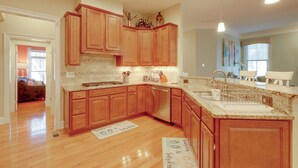 Una cocina amplia con armarios de madera, encimera de granito y lavavajillas integrado.