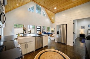 Una cocina moderna con armarios blancos, electrodomésticos de acero inoxidable y techo de madera.