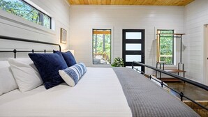 Une chambre avec un grand lit, un plafond en bois et une vue sur l’extérieur par une porte.
