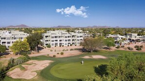 Un parcours de golf avec un club-house et des immeubles résidentiels en arrière-plan.