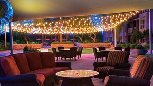 Un espace extérieur aménagé en terrasse, avec des meubles en osier, une table ronde et des guirlandes lumineuses.