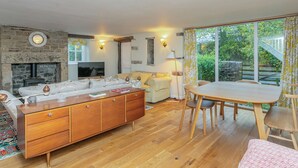 A cozy living room with a fireplace, a sofa, a dining table with chairs, and a television. - 3 bedroom accommodation in Broughton, near Skipton (Broughton, near Skipton)