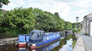 A narrow canal with boats docked along the side, surrounded by lush greenery and stone walls. - 3 bedroom accommodation in Broughton, near Skipton (Broughton, near Skipton)