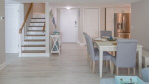 Une cuisine moderne équipée d’un réfrigérateur en acier inoxydable, d’une table à manger avec des chaises et d’un escalier menant à une autre pièce.