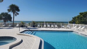 Un espace piscine avec des chaises longues et vue sur l’océan.