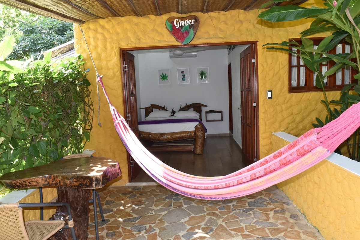 A room with a bed, a hammock, and a table.