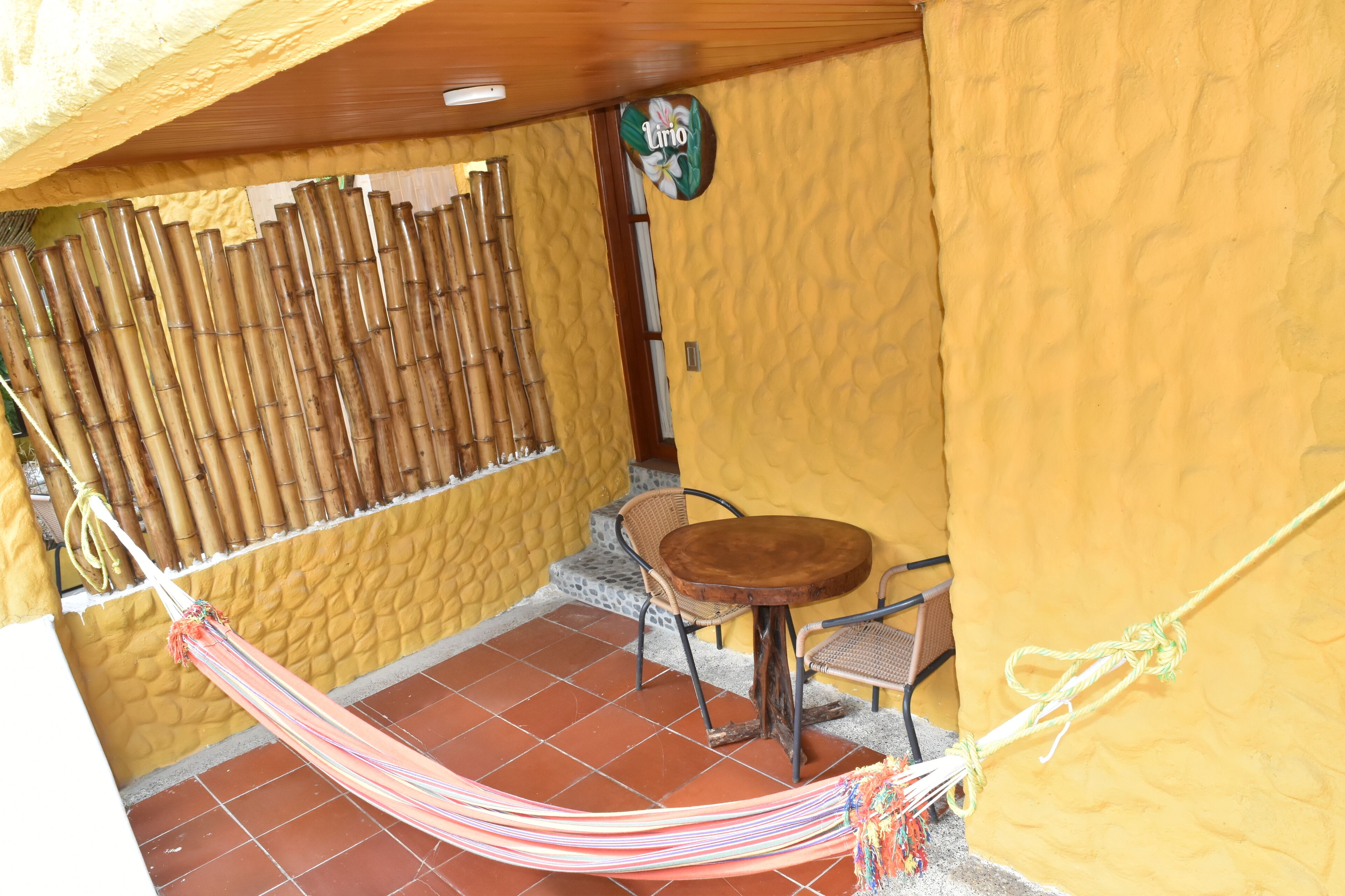 A small outdoor patio with a hammock, a table, and chairs.