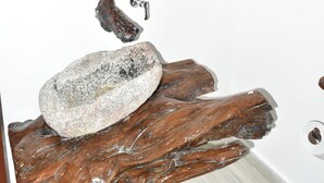 Un espejo de madera con diseño rústico, una piedra y una toalla sobre una superficie de madera.