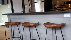 A kitchen with three wooden bar stools, a stainless steel refrigerator, and a built-in oven. - Modern,  but cozy apartment with spectacular views of the Bitterroot mountains (Stevensville)