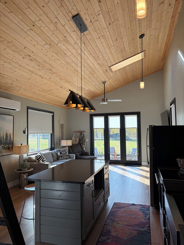 A modern kitchen with a central island, a dining area with a sofa, and a view of the outdoors.