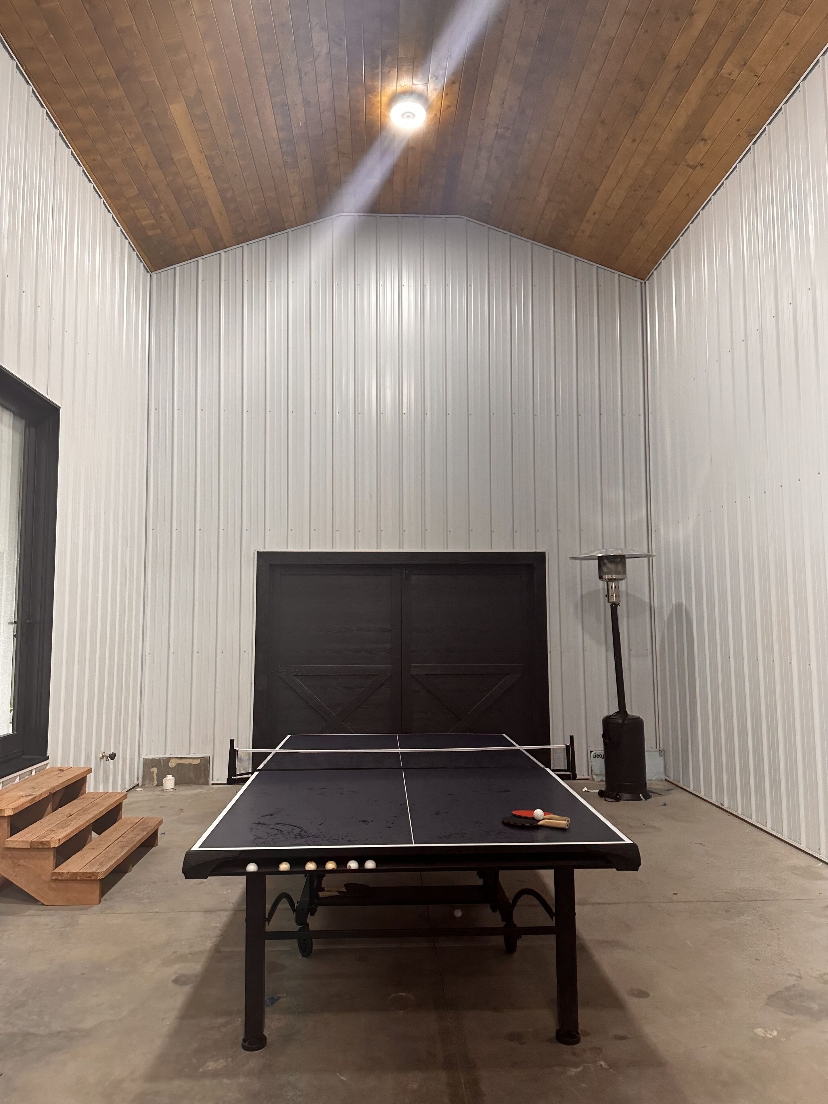 A ping pong table in a room with a high wooden ceiling and white walls.