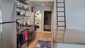 A modern kitchen with stainless steel appliances, a wooden floor, and a colorful rug. - Modern,  but cozy apartment with spectacular views of the Bitterroot mountains (Stevensville)