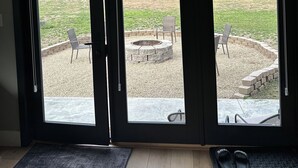 A room with a sliding glass door leading to an outdoor patio with a fire pit, seating, and a gravel area. - Modern,  but cozy apartment with spectacular views of the Bitterroot mountains (Stevensville)