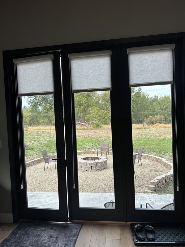 A room with a sliding glass door leading to an outdoor patio with a fire pit, seating, and a gravel area. - Modern,  but cozy apartment with spectacular views of the Bitterroot mountains (Stevensville)
