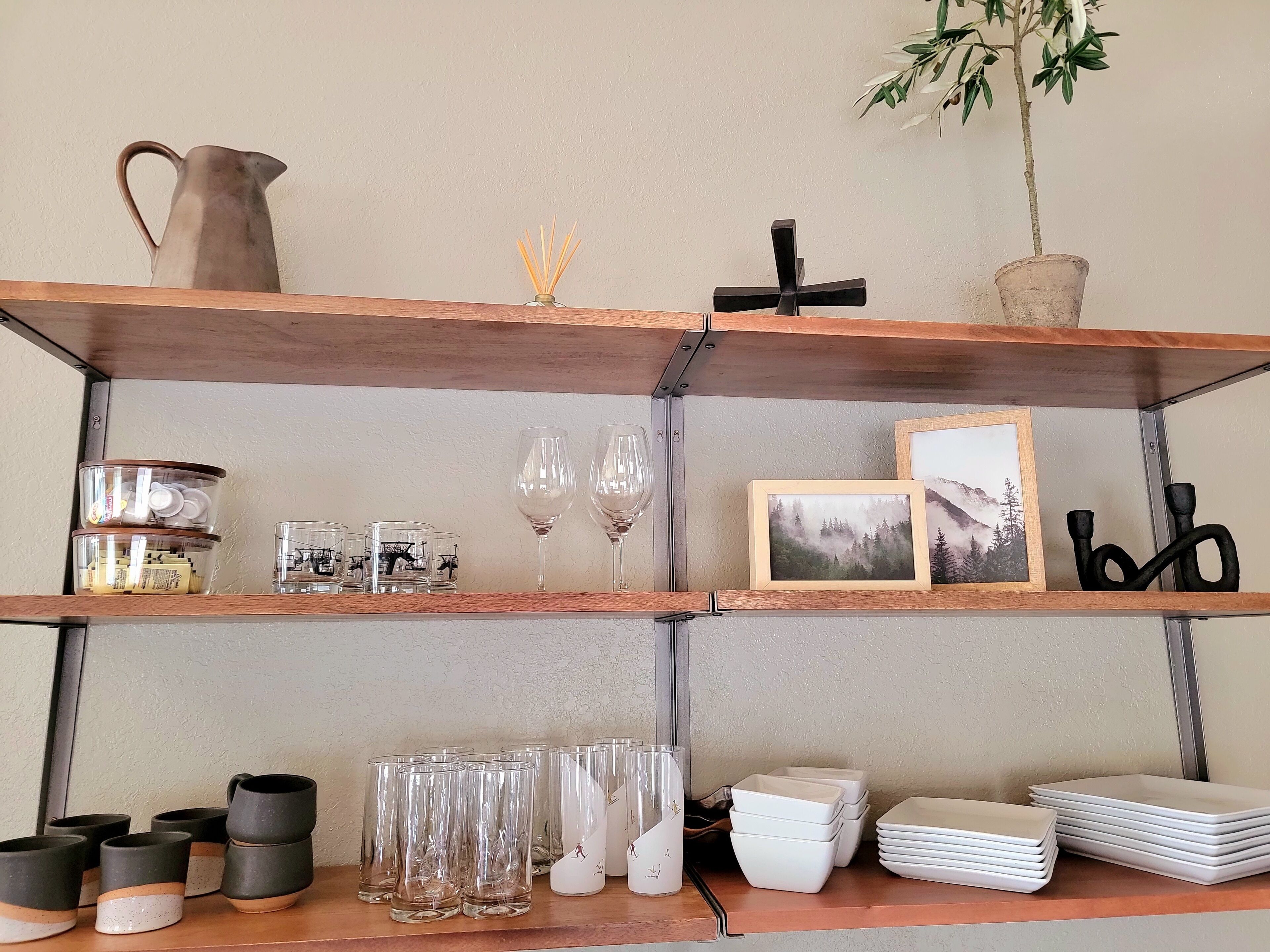 A shelf with various glassware, including wine glasses and tumblers, and a framed picture.