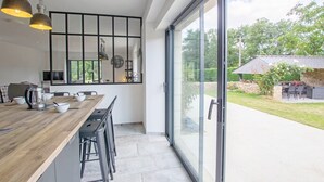Eine moderne Küche mit Holzarbeitsplatte, schwarzen Barhocker und Pendelleuchten.