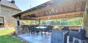 An outdoor patio with a stone wall, a table, and chairs.