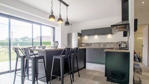 Eine moderne Küche mit einer großen Kochinsel, Barhocker und Blick ins Freie.